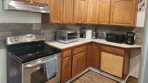 A kitchen with wooden cabinets, a stainless steel stove, a microwave, and a coffee maker. - Downtown and secluded (Manchester)