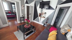 A modern living room with a dark grey sofa, a glass coffee table, and a wooden floor. - Downtown and secluded (Manchester)