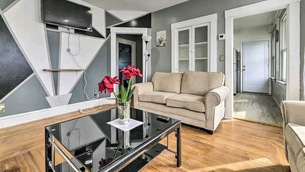 A modern living room with a sofa, a glass coffee table, and a TV mounted on a wall. - Downtown and secluded (Manchester)