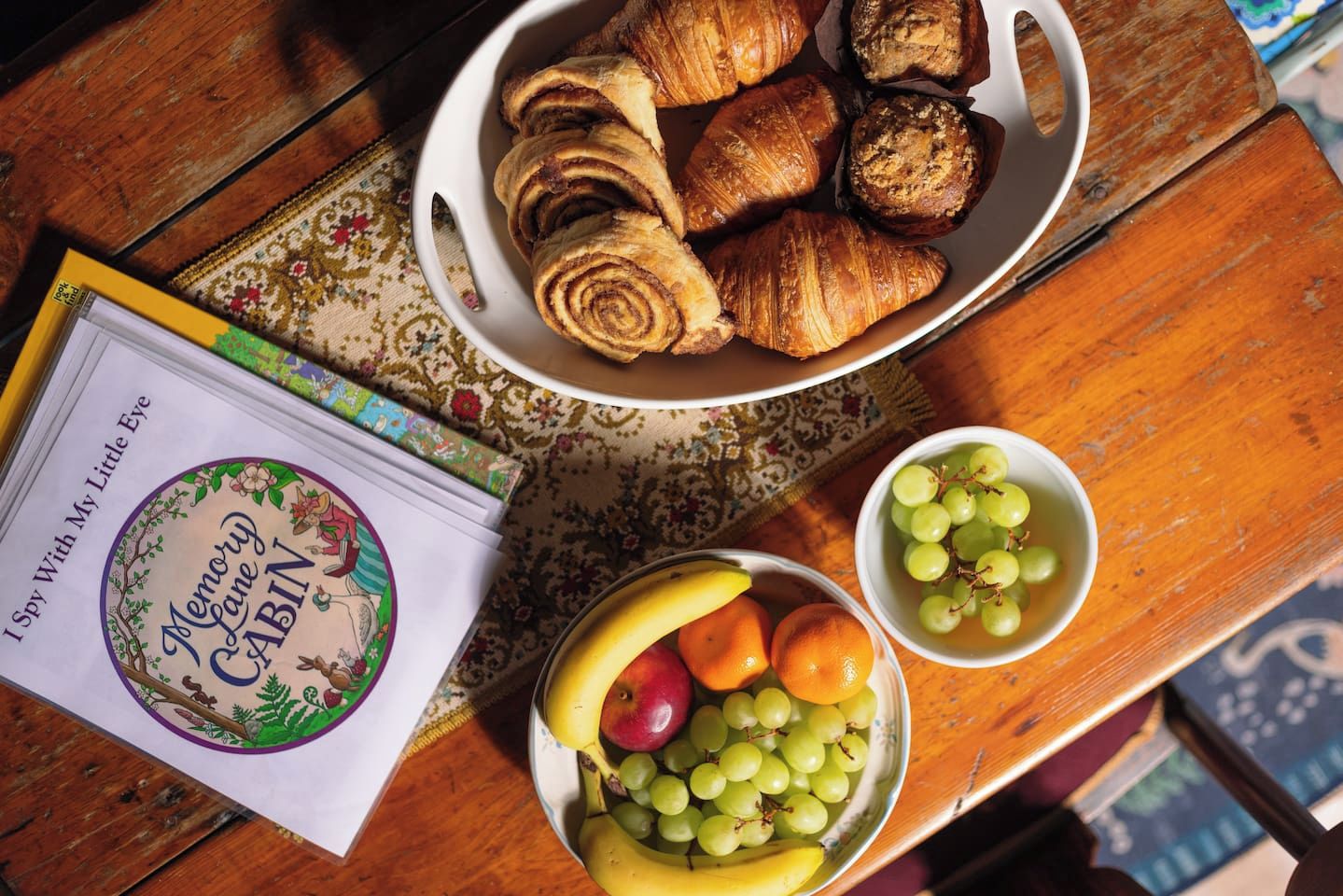 Una mesa con un bol de pasteles, un bol de fruta y un libro titulado 'I Spy With My Little Eye'.