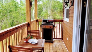 A wooden deck with a grill, a table with chairs, and a potted plant. - Miracles on Polly - Memory Lane Cabin (Belfast)