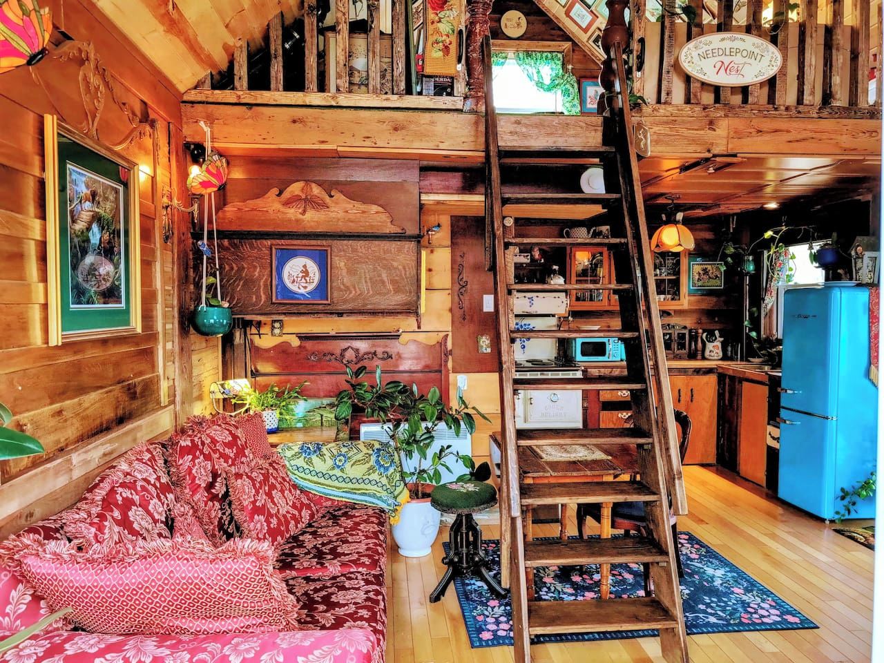 Ein gemütliches Blockhausschlafzimmer mit einer Holztreppe, einer Couch, einem Esstisch und einer Küchenzeile.