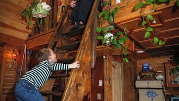 Eine Holztreppe, auf der eine Person nach oben geht. Esstisch mit einer Speiseplatte und einem Stuhl.