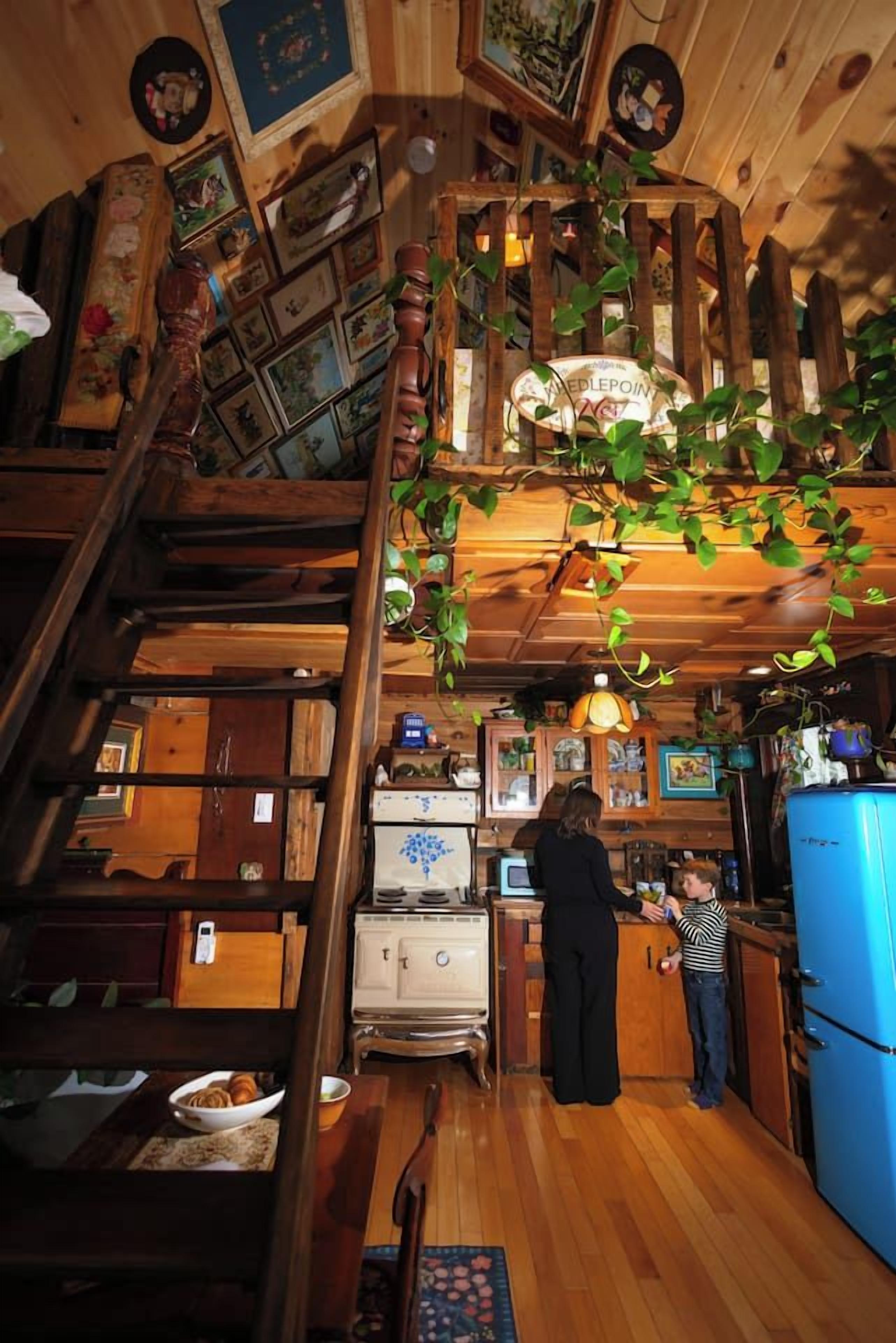 A rustic kitchen with wooden beams, a staircase, and a hanging plant.