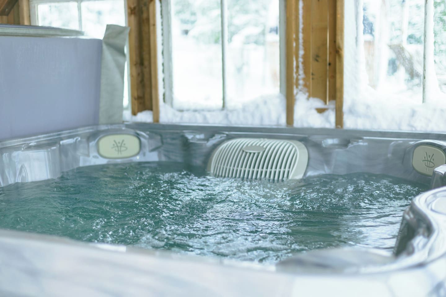 A hot tub with a wooden interior and a view of trees outside.