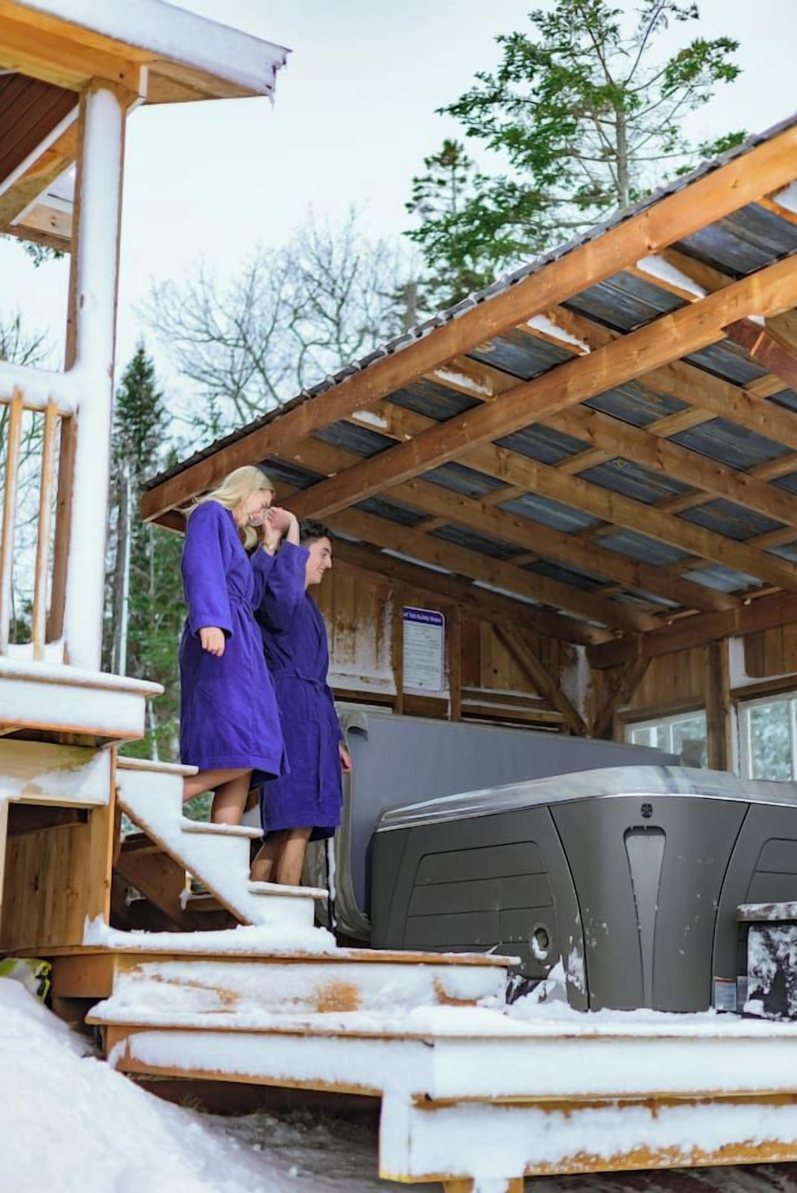 A wooden structure with a metal roof, a gray vehicle, and steps leading to a covered area.