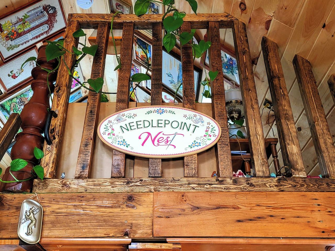 A wooden structure with a sign that reads 'Needlepoint Nest.'