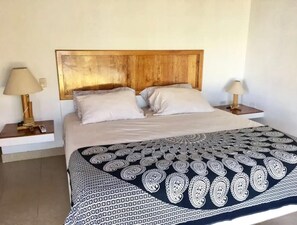 A double bed with a wooden headboard, two bedside tables with lamps, and a patterned bedspread.