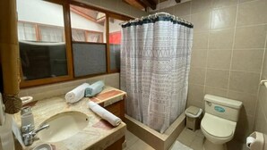 Un baño con lavamanos, inodoro, cortina de ducha y ventana.
