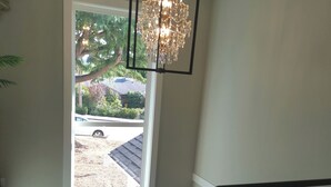 Eine Treppe mit einem gemusterten Teppich, einem Chandelier und Blick auf eine Wohngegend.
