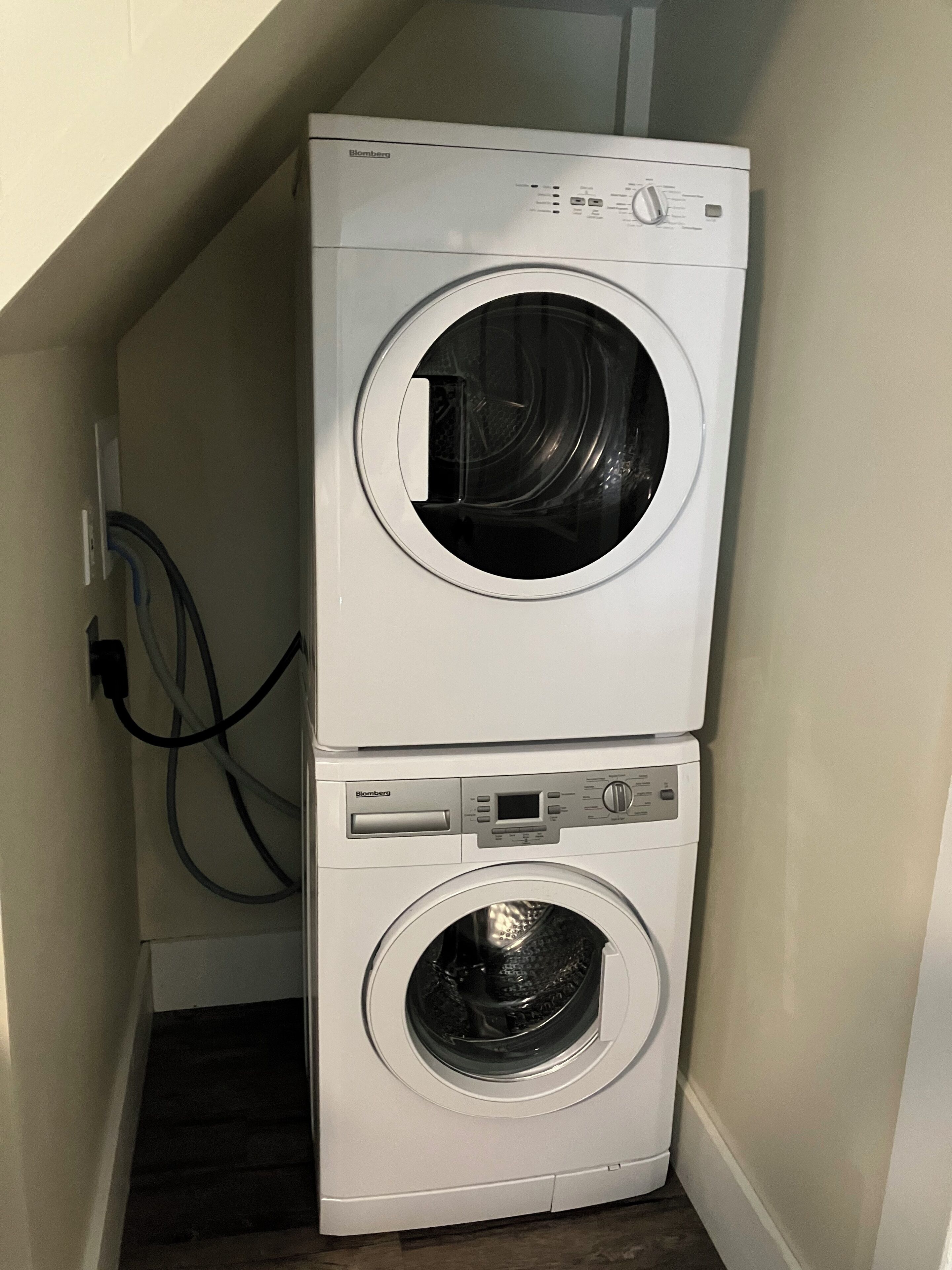A stacked washer and dryer unit in a corner of a room.