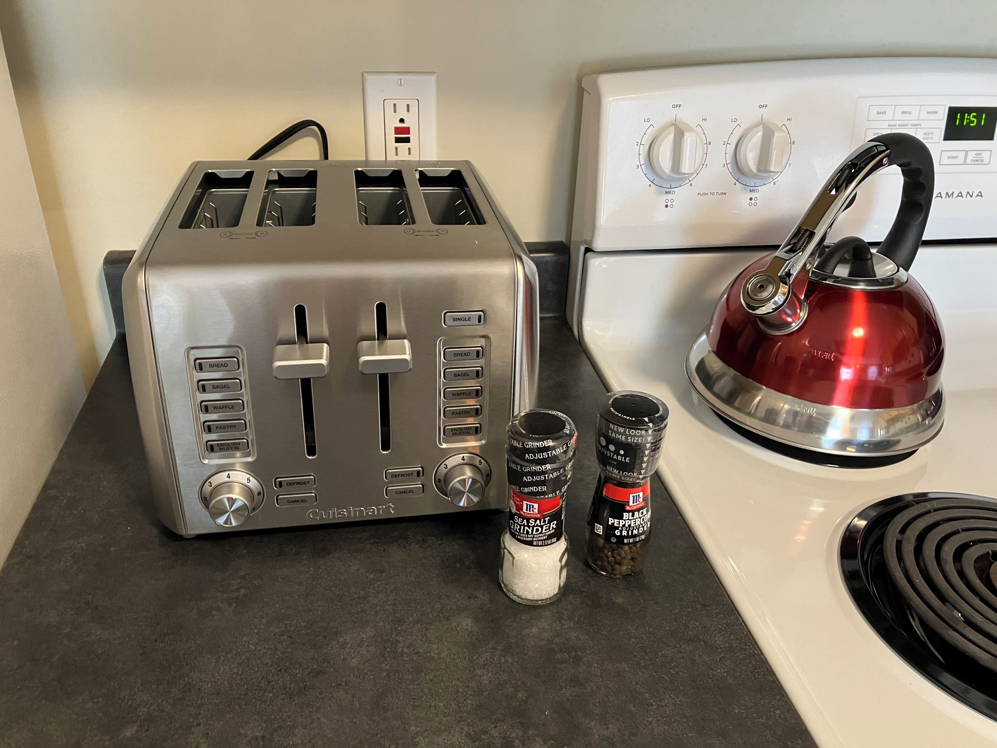 A kitchen with a toaster, a kettle, and two spice jars.