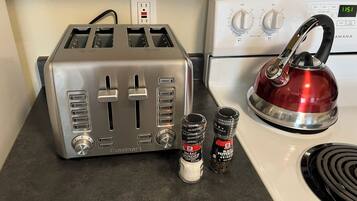A kitchen with a toaster, a kettle, and two spice jars.