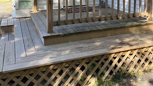 Une terrasse en bois avec une porte blanche, une boîte aux lettres et un petit banc.