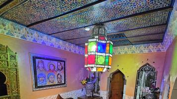 A room with a patterned floor, a wooden cabinet, a hanging lantern, and a wall with a framed picture.