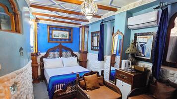 A room with a bed, a sofa, a small table, and a decorative floor pattern.