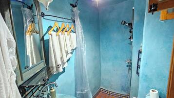 A bathroom with a blue wall, a patterned sink, a toilet, and a shower area.