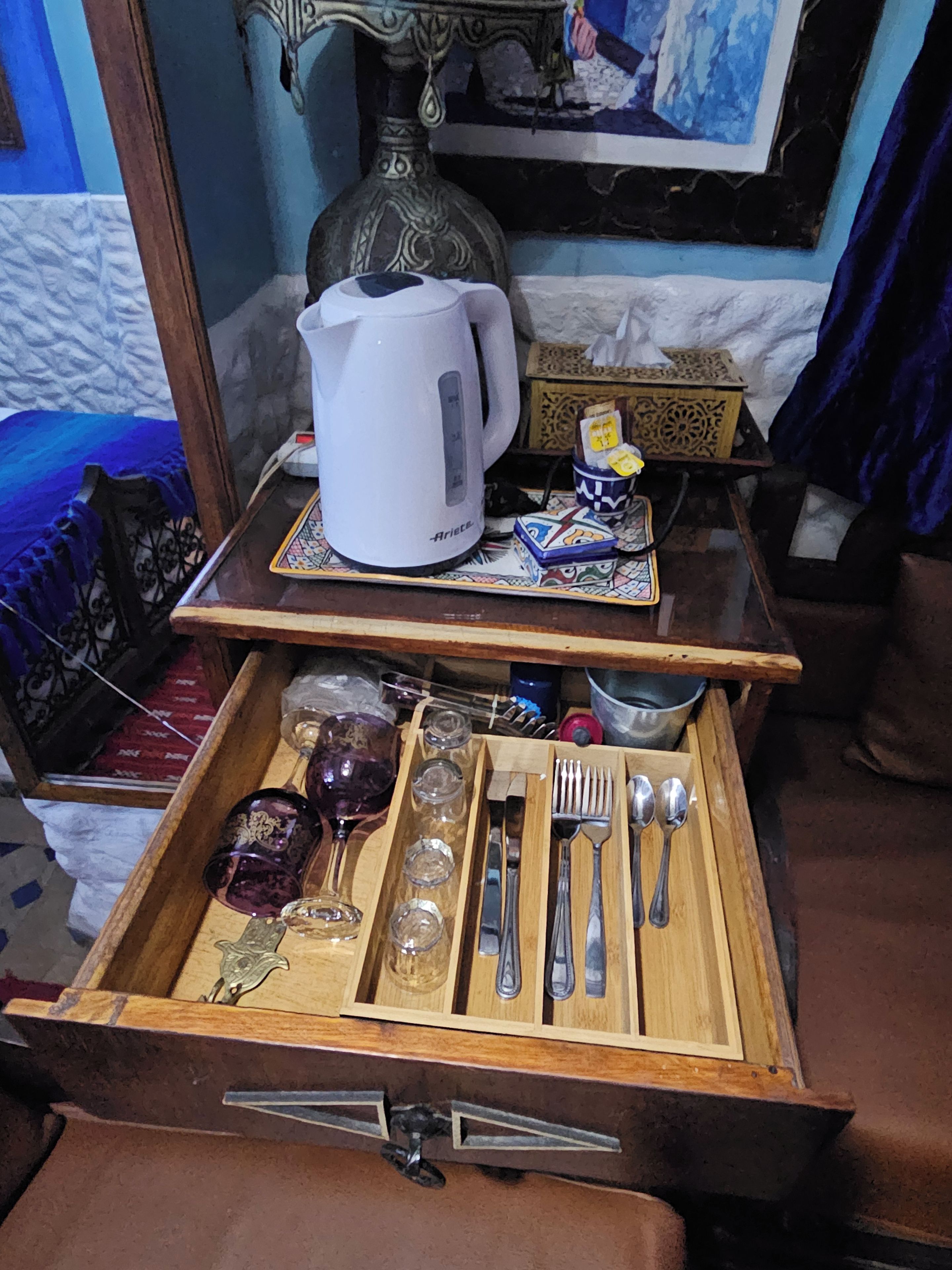 A wooden tray with a white electric kettle, a small box, and a decorative item on a table.