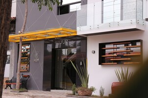 Un edificio moderno con fachada de vidrio, un elemento estructural amarillo y un cartel que dice "THE LU'UM HOUSE".
