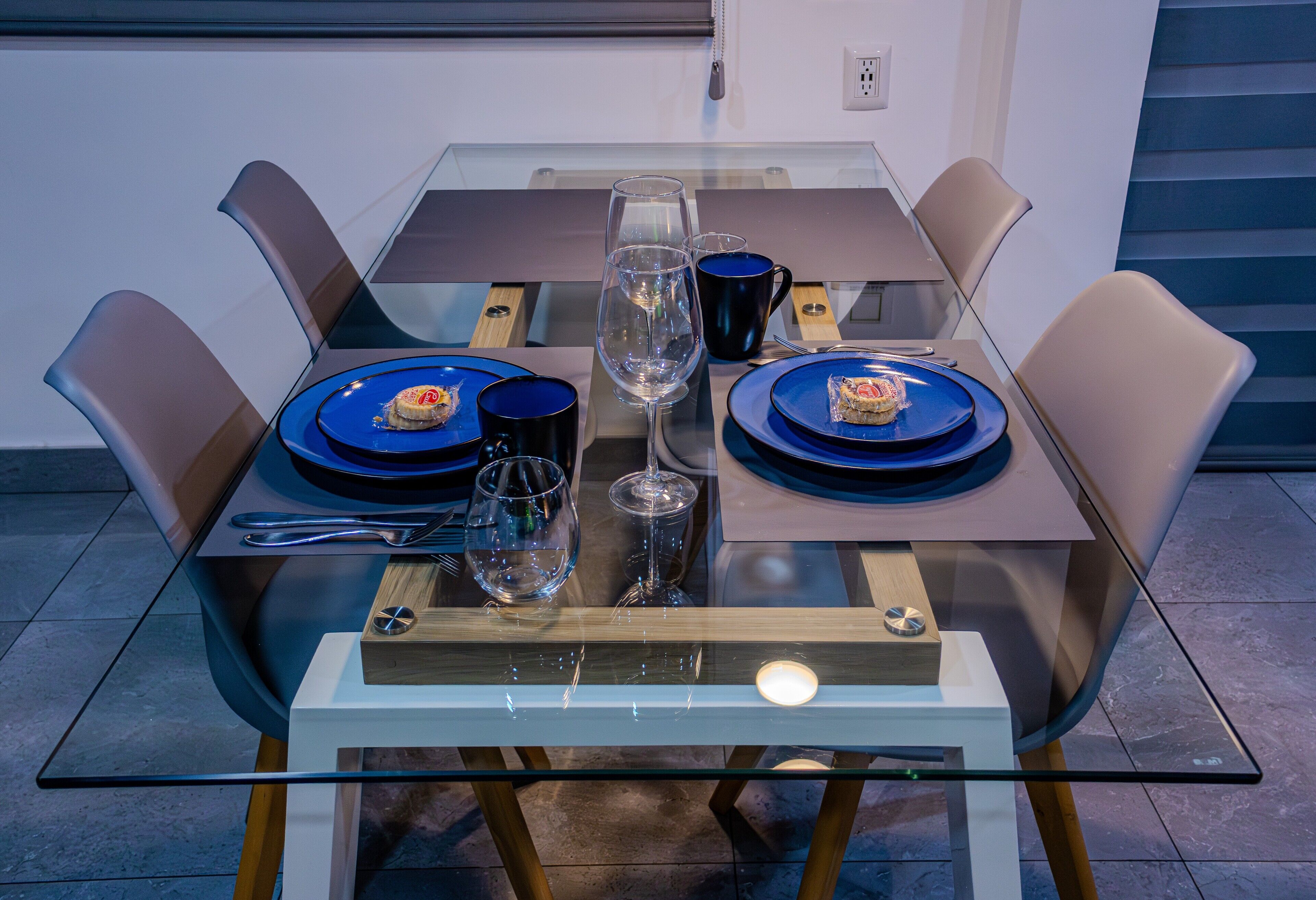 A modern dining table with blue plates, a clear wine glass, and a candle.