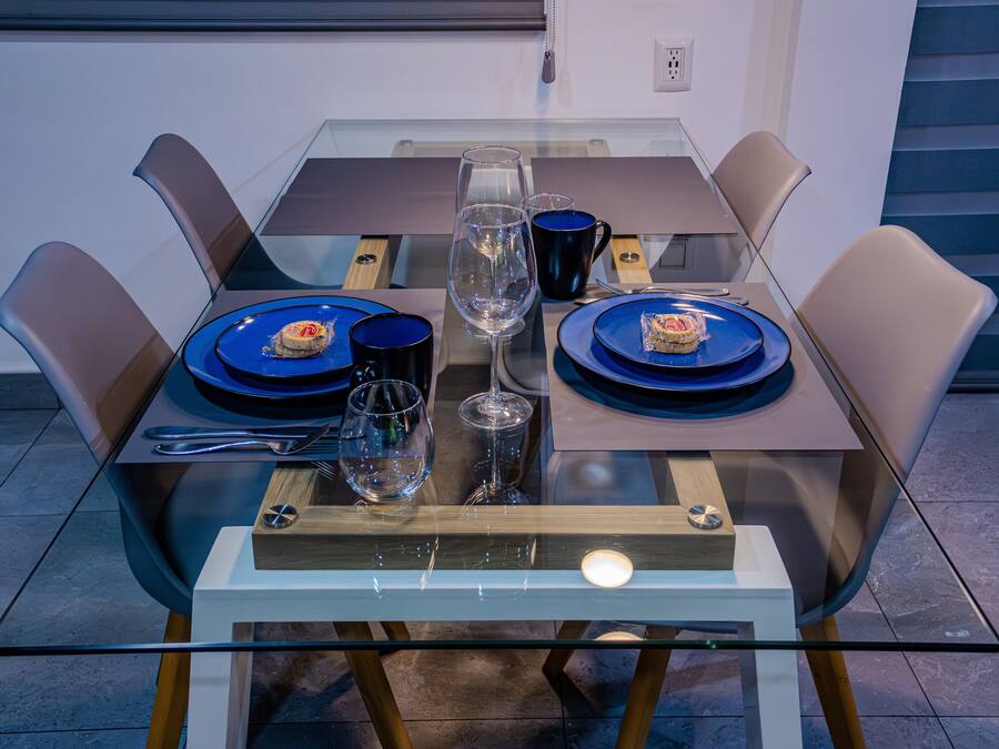 A modern dining table with blue plates, a clear wine glass, and a candle.