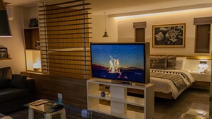 A modern living room with a flat-screen TV, a sofa, a coffee table, and a bed with a nightstand. - The Lu'um House (Tuxtla Gutierrez)