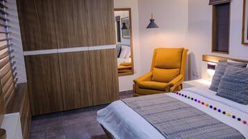 A modern bedroom with a bed, a wooden wardrobe, a chair, and a mirror.