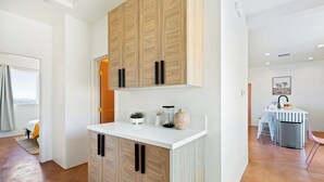 Eine moderne Küche mit Holzausstattung, einer weißen Arbeitsplatte und einem Essbereich mit Tisch und Stühlen.