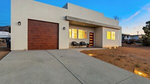 Ein modernes Haus mit einer großen Garage, einer überdachten Veranda und einem gut beleuchteten Eingang.