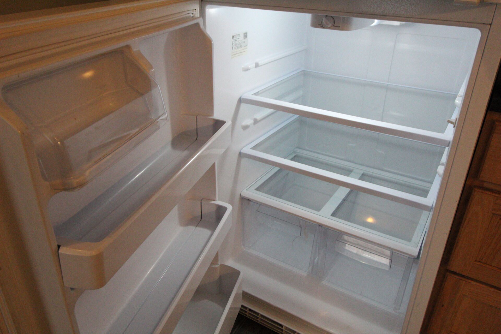 An empty refrigerator with multiple shelves and a freezer compartment.