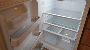 An empty refrigerator with multiple shelves and a freezer compartment.