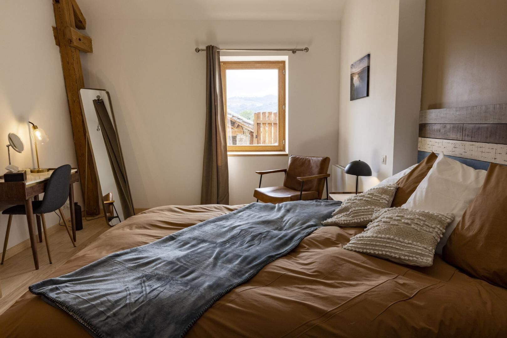 A bedroom with a bed, a desk, a chair, and a window with a view.