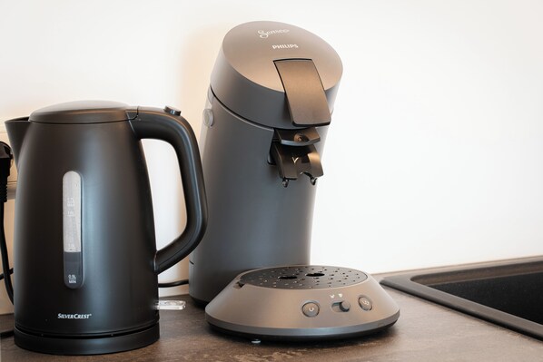 Una cocina moderna con cafetera, hervidor y dispensador de agua.