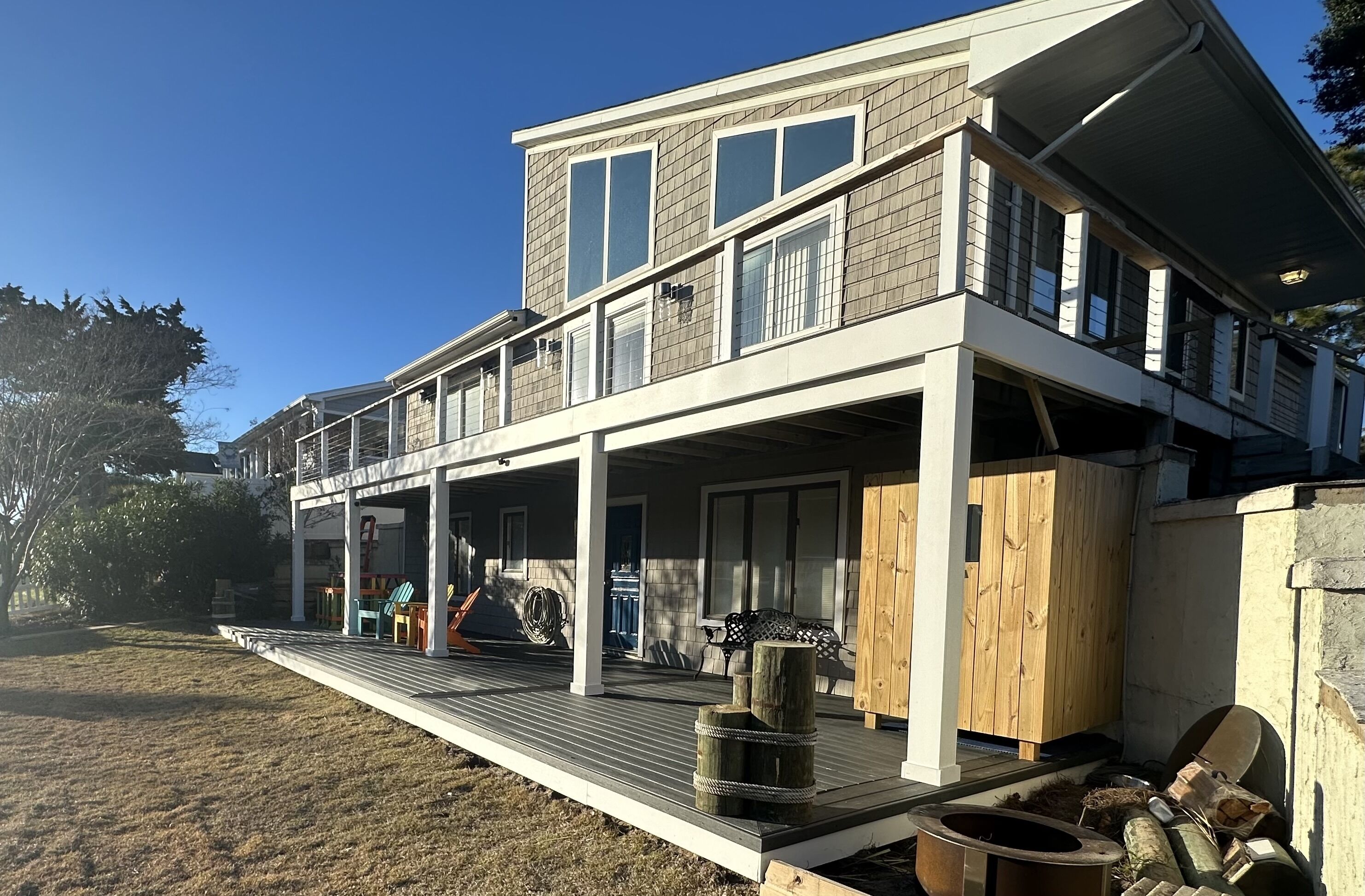 Een modern huis met twee verdiepingen, een overdekte veranda, een terras en een groot raam op de bovenverdieping.
