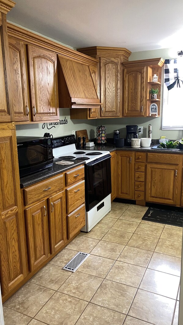 Kitchen with a central island, stove, microwave, and appliances, offering a view of the outside through the window.