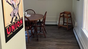 A dining area with a wooden table and chairs, a mirror on the wall, and a poster on the wall. - Lots of Space for a Great Price! Barre VT! (Barre)