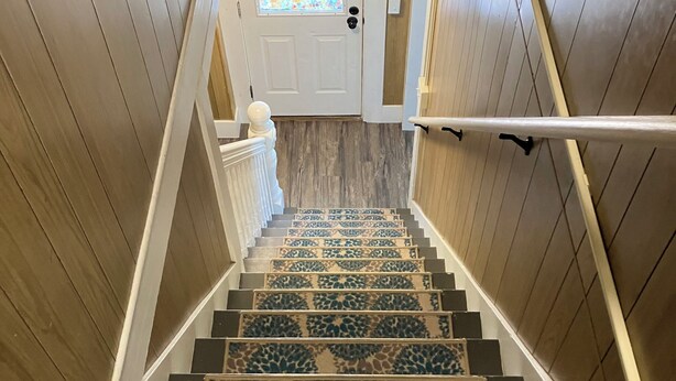 A wooden staircase with patterned carpet, white railings, and a door with a stained glass window. - Lots of Space for a Great Price! Barre VT! (Barre)