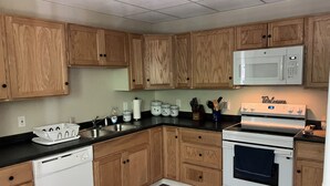 A kitchen with wooden cabinets, a white dishwasher, a white stove, and a microwave. - Lots of Space for a Great Price! Barre VT! (Barre)