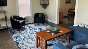 A living room with a blue sofa, two black chairs, a wooden coffee table, and a patterned rug. - Lots of Space for a Great Price! Barre VT! (Barre)