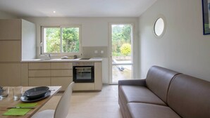 A modern kitchen with a built-in oven, a dining area with a table and chairs, and a living area with a sofa.