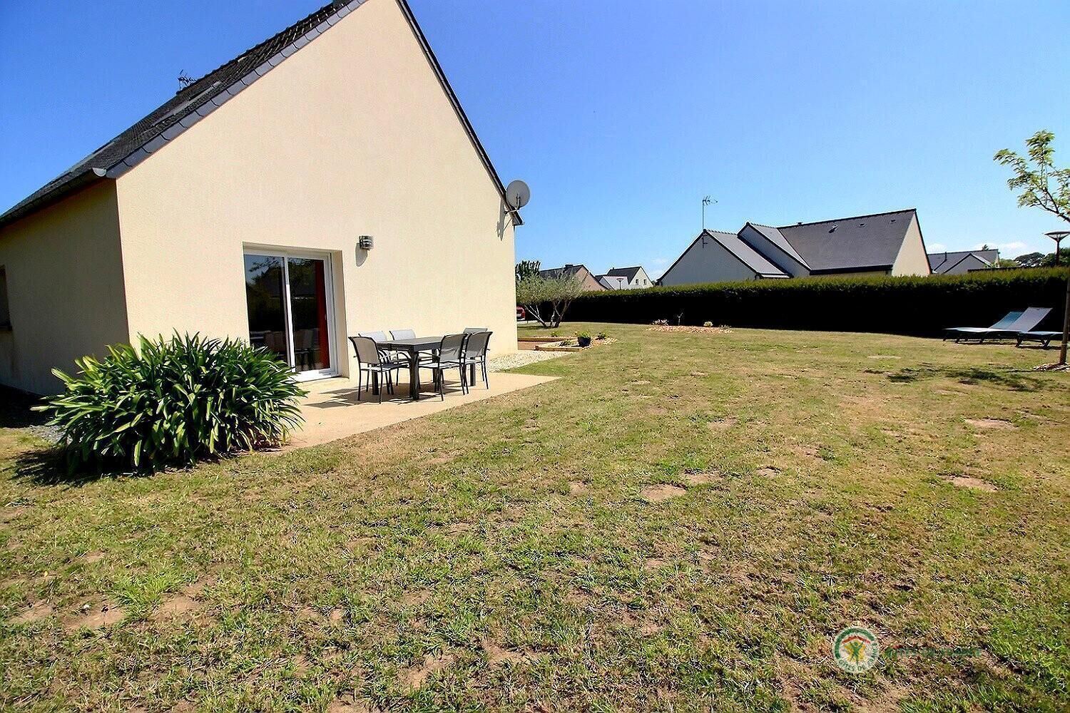 Une maison de plain-pied avec un patio, une petite pelouse et une antenne parabolique.