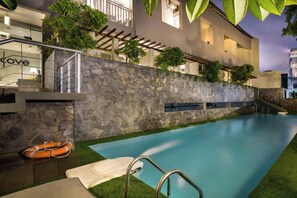 A modern hotel with a stone wall, a swimming pool, and a lifebuoy. - Cove Birah Senopati (Jakarta)