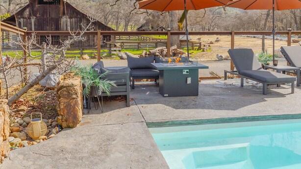 A backyard with a swimming pool, lounge chairs, a fire pit, and a rustic wooden barn. - Coyote Creek Ranch + Pool House near Murphy’s (Vallecito)