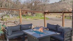 An outdoor patio with a fire pit table, two sofas, and a large umbrella. - Coyote Creek Ranch + Pool House near Murphy’s (Vallecito)