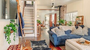 A living room with a blue sofa, a wooden ladder, and a staircase. - Coyote Creek Ranch + Pool House near Murphy’s (Vallecito)