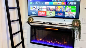 A flat-screen TV mounted on a wall with a fireplace below it. - Coyote Creek Ranch + Pool House near Murphy’s (Vallecito)