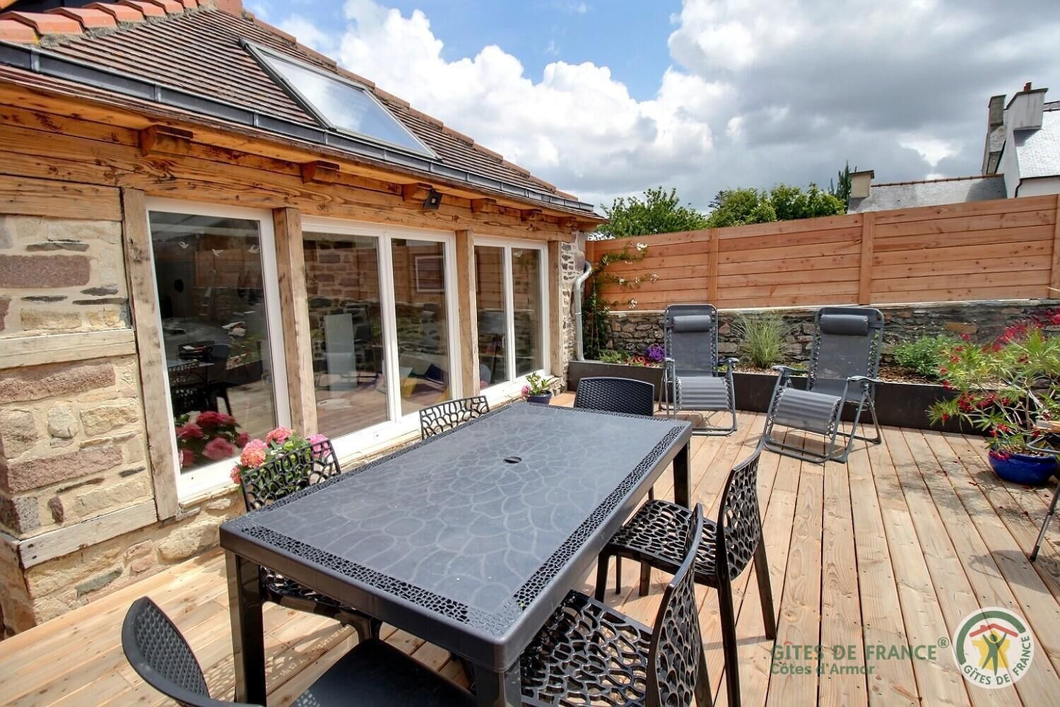 A patio with a table and chairs, a stone wall, and a wooden fence.