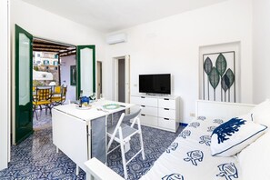 Ein kompaktes Hotelzimmer mit Bett, Fernseher, Schreibtisch mit Stuhl und einem kleinen Balkon mit Tisch und Stühlen.
