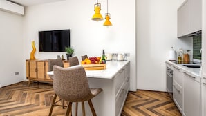 Una cocina moderna con una isla central, armarios blancos y un televisor de pantalla plana montado en la pared.