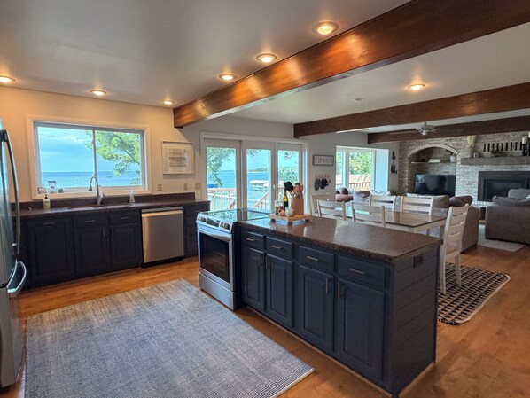 A modern kitchen with dark cabinets, a central island, and a view of the ocean.